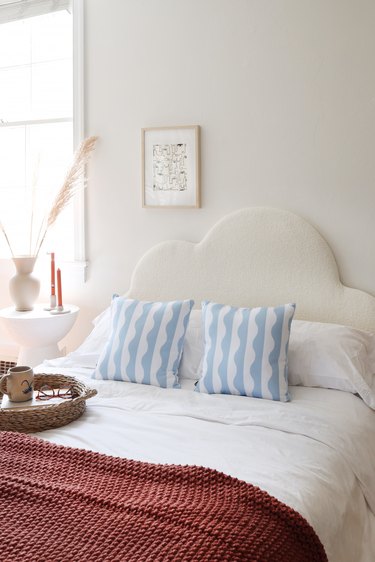 DIY boucle upholstered cloud headboard styled with throw pillows and bedroom accessories