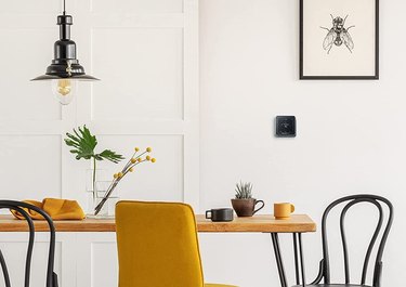 Black Honeywell Home RCHT8610WF2006/W, T5 Smart Thermostat on wall of modern white dining room