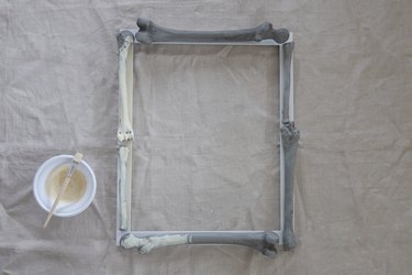 Painting plastic bones on frame with an ivory-hued plaster paint