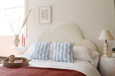 DIY boucle upholstered cloud headboard styled with throw pillows and blankets