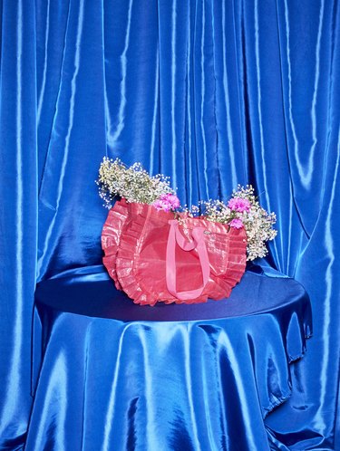 pink ikea bag with flowers on blue pedestal with blue background