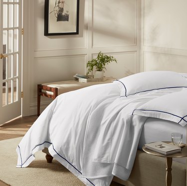 white bedding on bed in bedroom with bench