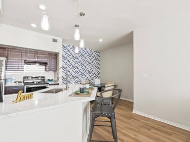 White kitchen with stools, a white countertop, and hardwood floors in El Paso, Texas.