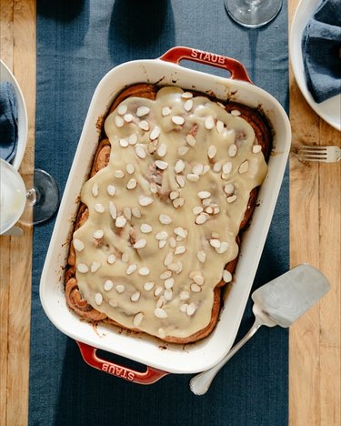 Apple and honey marzipan rolls in a white dish on a navy blue cloth over a wooden table.