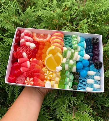 person holding box with rows of rainbow candy