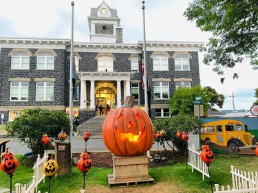 Set of Halloweentown in St. Helens, OR with a giant jack-o'-lantern in front of a grey building.