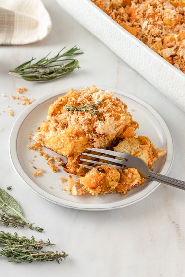 A yellow and orange squash bake on a white plate topped with toasted bread crumbs.
