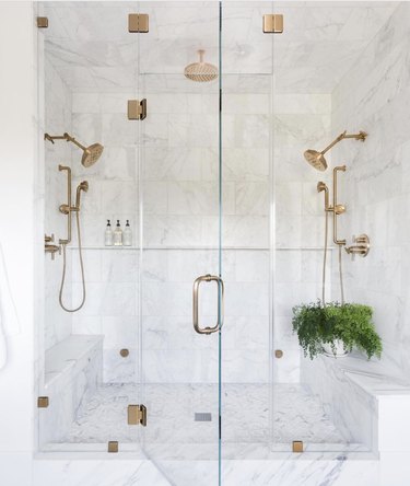 Glam bathroom with rain shower head, marble tile and gold hardware.