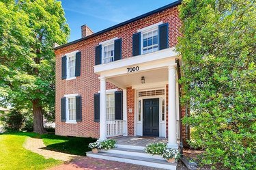 A brick house with black shutters and a white porch with columns in Gaithersburg, MD.