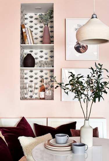 pink breakfast nook with plum-colored pillows and built-in wall nook shelving