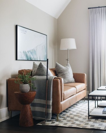 A caramel leather couch grounds an office space with neutral accents.