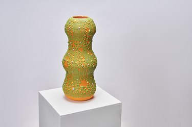 an orange vase with green textured speckles