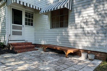 Messy and weathered "before" photo of porch area with leaves, weeds, and mildew