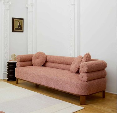 pink curved sofa in white-walled room