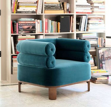 teal club chair in front of bookshelf