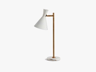 A midcentury-style table lamp with a white carrara marble base, aged brass pole, and powder coated steel shade.