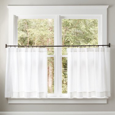 A black cafe curtain rod with sheer curtains