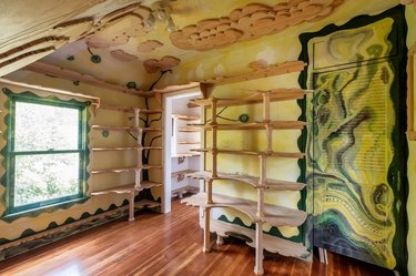 Room with wooden shelves and designs on the ceiling, features a green door