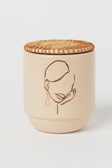 candle with illustration of a person and rattan lid
