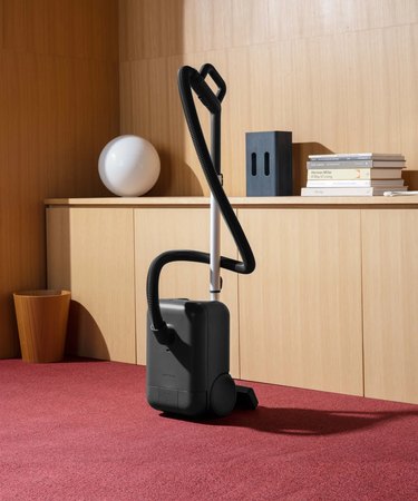 minimalist vacuum in room with red carpet and wood walls