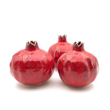 Three red ceramic pomegranates on a white background.