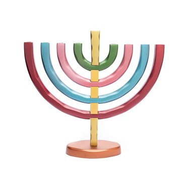 A colorful menorah with a gold stem and white base on a white background.