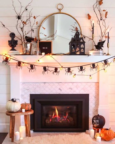 mantel with Halloween decor including spider garland and twinkle lights