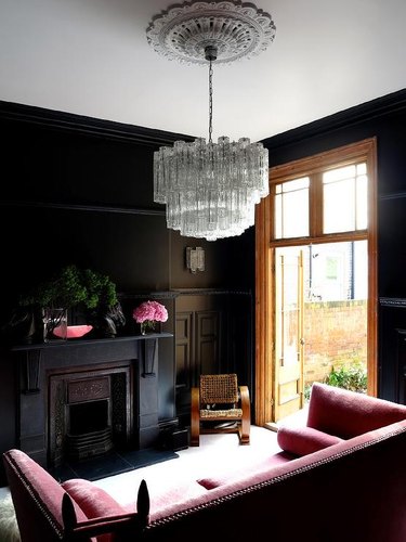 den with brown walls, black fireplace and pink sofa