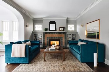 Living room with light gray walls, real sofa and brown rug and flooring