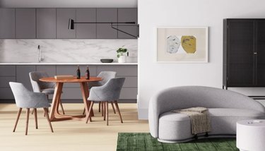 Image of a Scandinavian style room with a dining table in the background and a gray couch in the forefront.