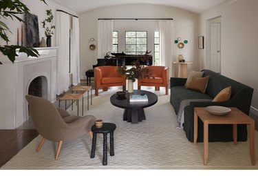 living room with orange chairs, black sofa and brown accents