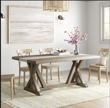 Image of rectangular farmhouse style dining table with three chairs around it.