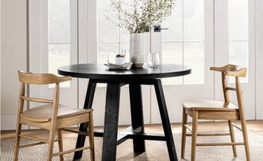 Image of a black scandi style table with two light colored chairs aroung it.