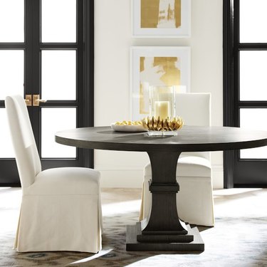 Image of a round dining table surrounded by white chairs.