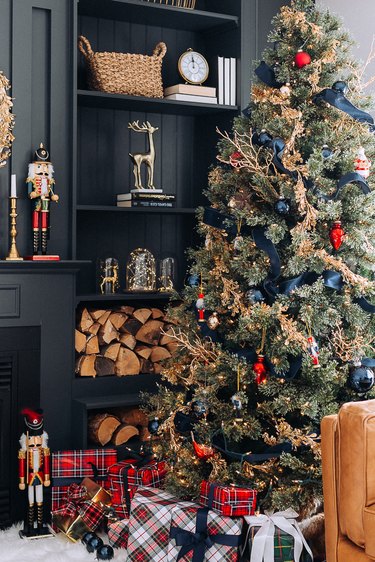 Navy living room with Christmas tree with navy ribbon, gold tinsel, and red presents.