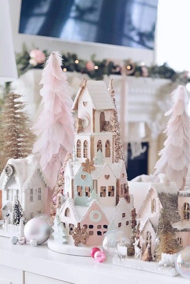 Pastel and glitter houses and brush bottle trees in a Christmas village.