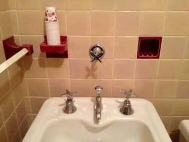 An ice water tap above the bathroom sink in a 1930s home, complete with built-in Dixie cup storage.