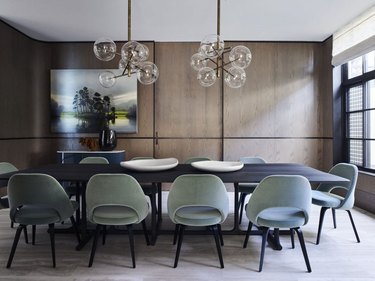 dining room with wood built-ins, a black table and mint green chairs