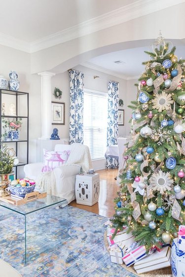 Blue and white living room with a Christmas tree featuring huge blue and white ornaments.