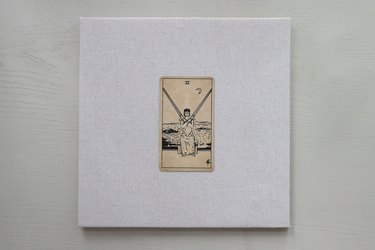 Tarot card attached to the center of a linen backing board