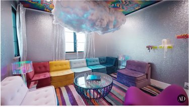 A room with a rainbow couch and cloud-shaped chandelier