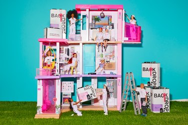 Barbie and Ken dolls holding Backdrop paint cans inside a Barbie Dreamhouse with a turquoise background.