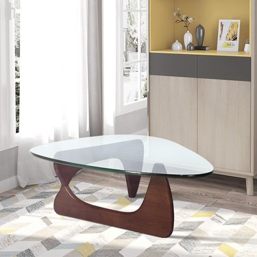 Glass-top coffee table. Top is an irregular triangle with rounded edges; base is sculptural wood veneer
