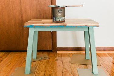 Turquoise wood bench with bucket of paint and paintbrush