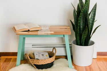 Turquoise-wood bench with white yarn, book, potted basket, sheeps rug
