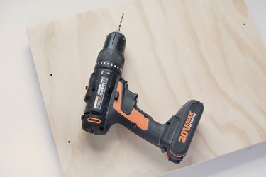 a power drill on a sheet of plywood with several holes drilled in it