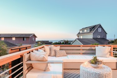 a deck with wrap-around patio furniture, a wicker table, and ocean views