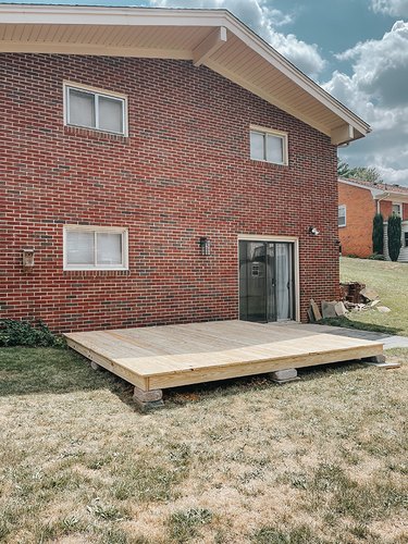 Wood platform deck on cement blocks and by a brick house
