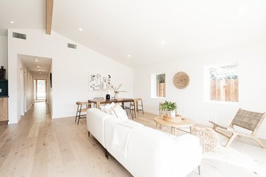 Minimalist living room with wood floors, white and neutral furniture, and fiber decor