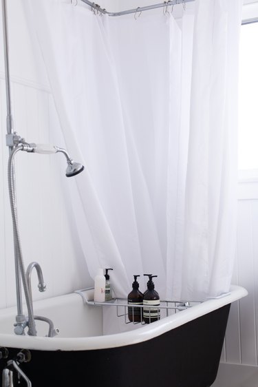 the walls, shower curtain, and most fixtures in this bathroom are white; the tub stark black